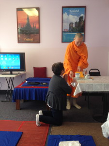 A sister gives Thai monk Luang Pi tea before he awakens his iPad.